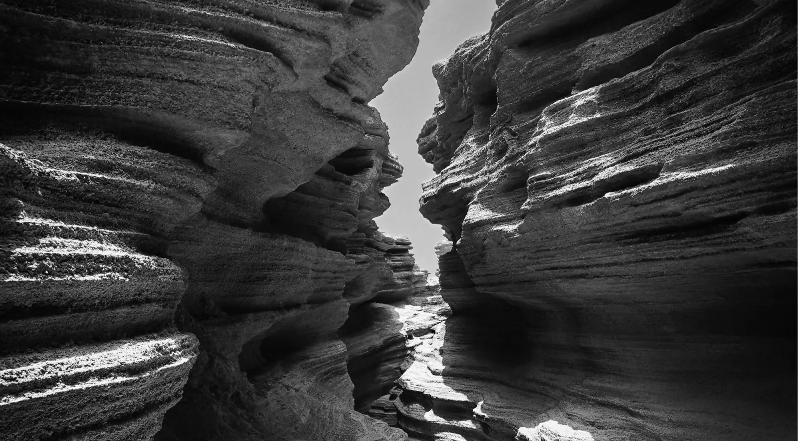 Black-and-white view up a narrow gully eroded into layered volcanic ash