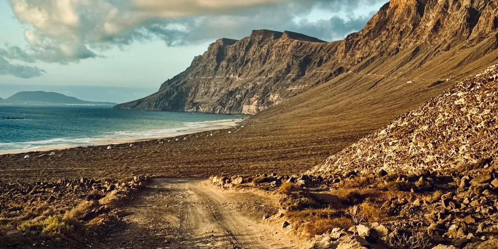 The Famara cliffs falling to a beach track on Lanzarote's windward coast