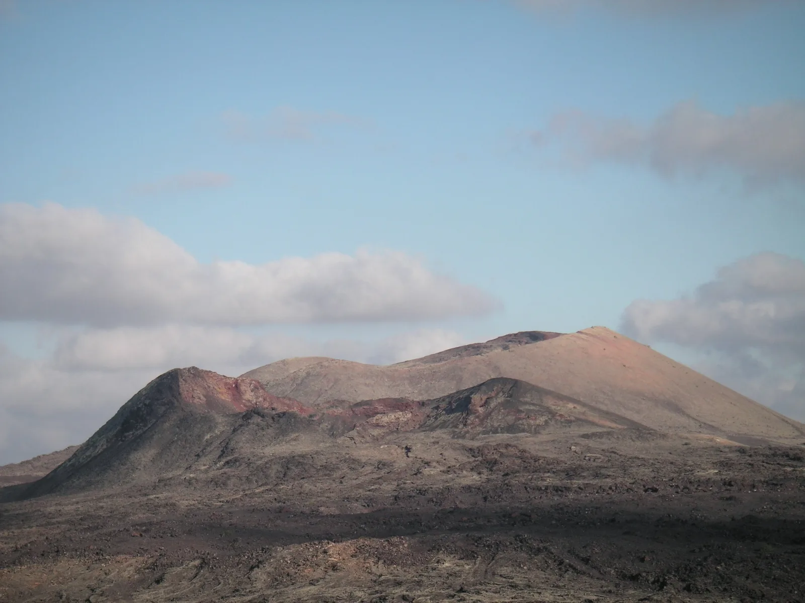 Twin volcanic cones rising from a dark lava flow under a clear Lanzarote sky